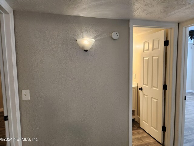 hallway with a textured ceiling and light wood-type flooring