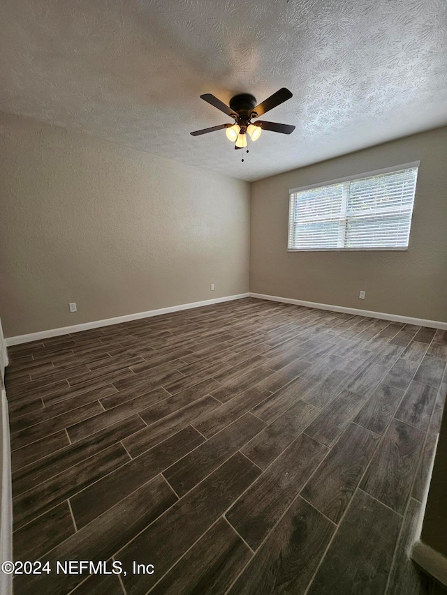 unfurnished room with a textured ceiling, dark wood-type flooring, and ceiling fan