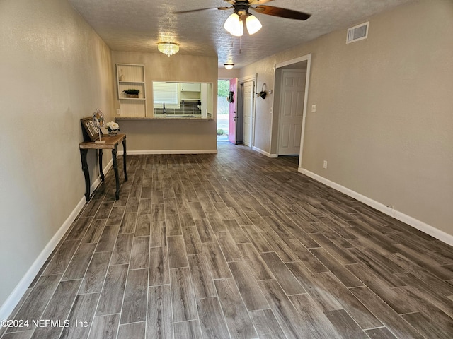 unfurnished living room with ceiling fan, a textured ceiling, and dark hardwood / wood-style flooring