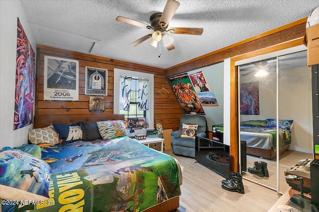 bedroom with wood walls, light hardwood / wood-style floors, and ceiling fan