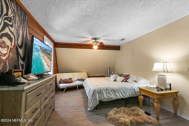 bedroom with ceiling fan, a textured ceiling, and dark hardwood / wood-style floors