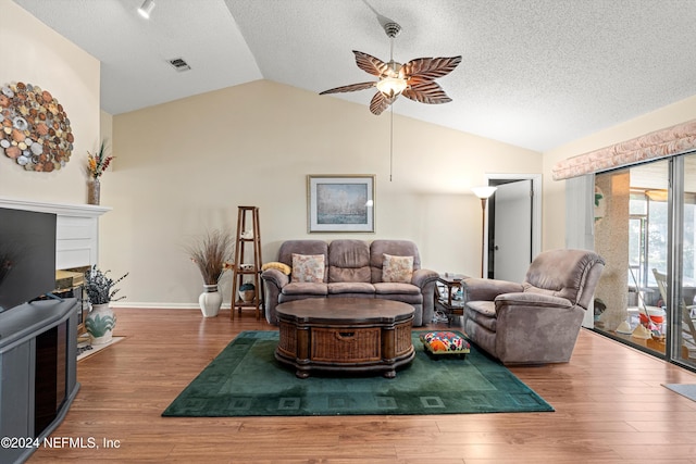 living room with hardwood / wood-style floors, ceiling fan, a textured ceiling, and vaulted ceiling