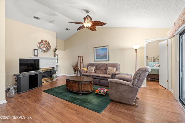 living room with ceiling fan, a textured ceiling, wood-type flooring, and vaulted ceiling