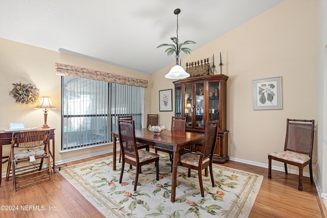 dining room featuring light wood-type flooring and vaulted ceiling