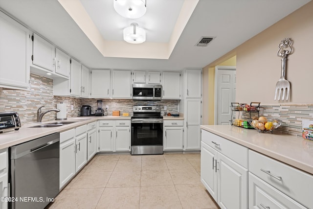 kitchen featuring white cabinetry, stainless steel appliances, sink, and decorative light fixtures