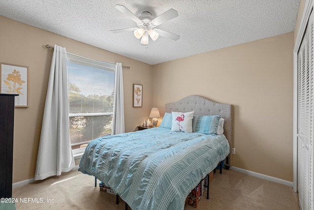 bedroom featuring a closet, ceiling fan, light carpet, and a textured ceiling