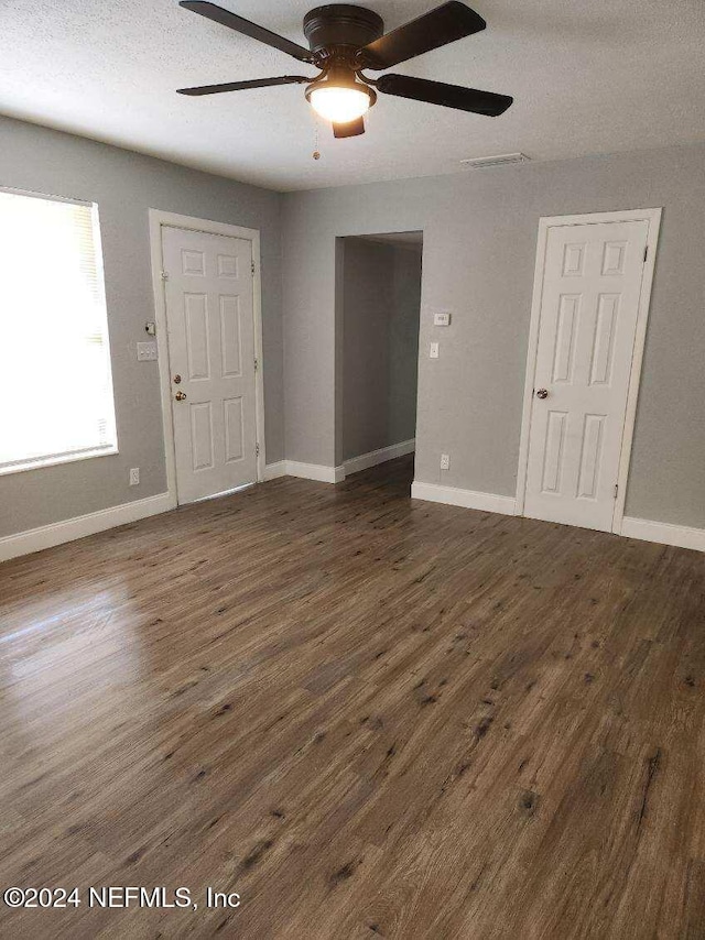 empty room with a textured ceiling, ceiling fan, and dark wood-type flooring