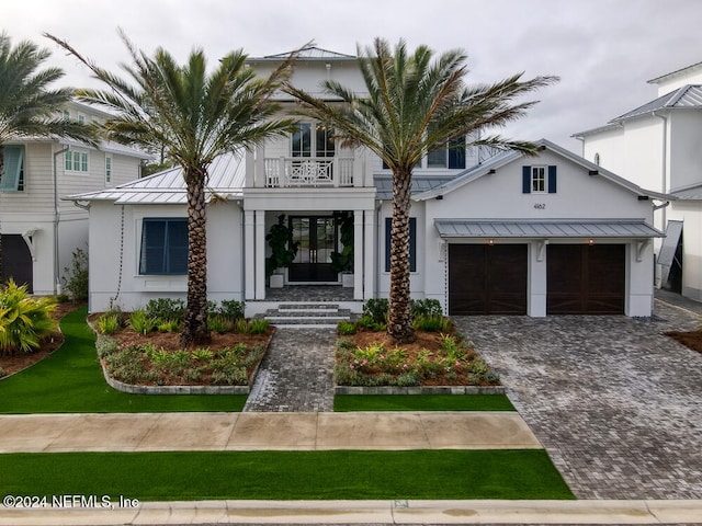 view of front of property featuring a balcony, a front lawn, and a garage