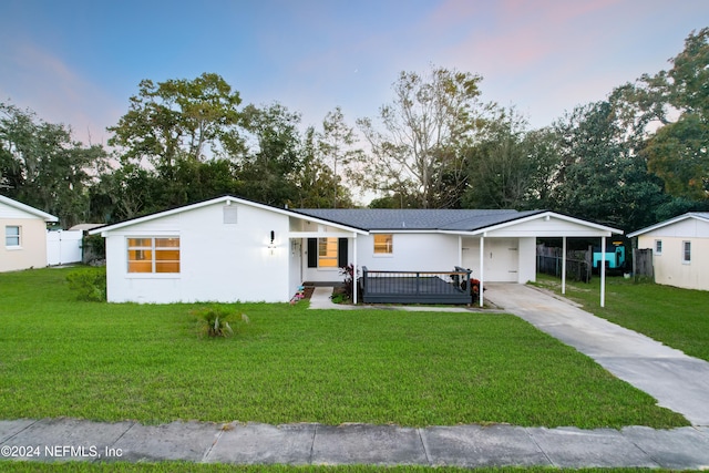 view of front of property featuring a yard, a garage, and a carport