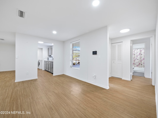 unfurnished living room featuring washer / clothes dryer and light wood-type flooring