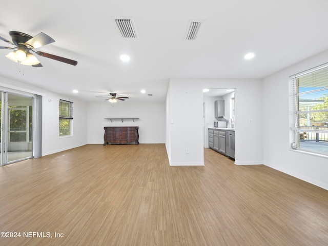 unfurnished living room with a healthy amount of sunlight, light wood-type flooring, and ceiling fan