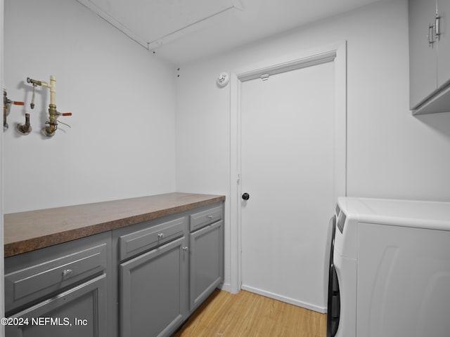 clothes washing area featuring light hardwood / wood-style floors and cabinets