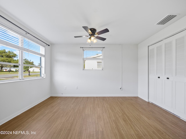 unfurnished bedroom featuring light hardwood / wood-style flooring, multiple windows, a closet, and ceiling fan