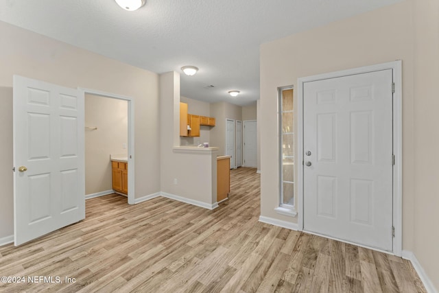 entryway with a textured ceiling and light wood-type flooring