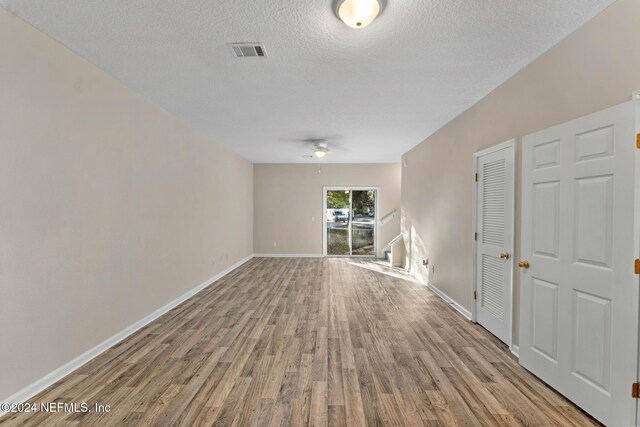 unfurnished room with a textured ceiling, light wood-type flooring, and ceiling fan