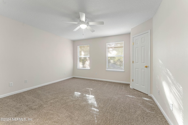 carpeted spare room featuring a textured ceiling and ceiling fan