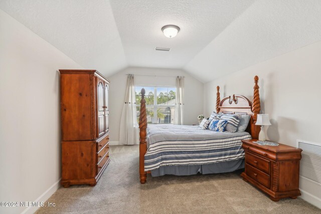 carpeted bedroom featuring lofted ceiling and a textured ceiling