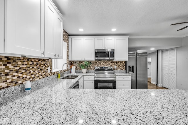 kitchen featuring sink, decorative backsplash, light stone counters, white cabinetry, and stainless steel appliances