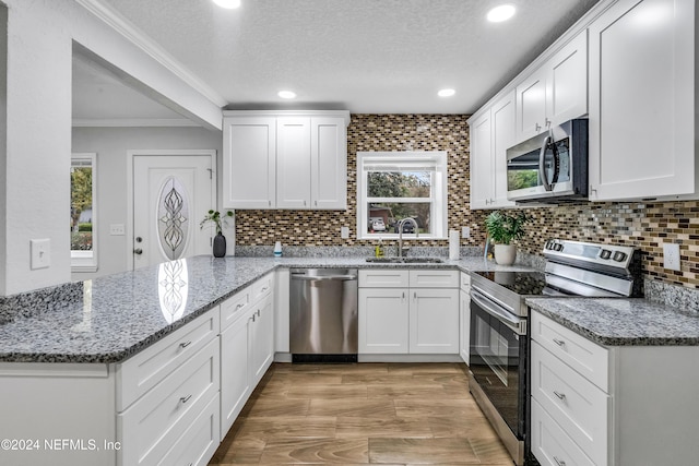 kitchen with white cabinets, crown molding, a textured ceiling, and appliances with stainless steel finishes