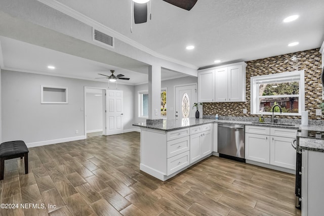 kitchen with kitchen peninsula, stainless steel dishwasher, stone counters, light hardwood / wood-style floors, and white cabinetry