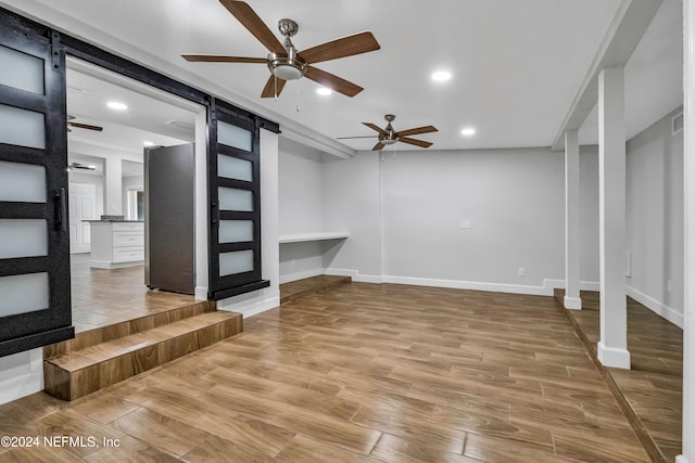 interior space with hardwood / wood-style flooring, ceiling fan, and a barn door