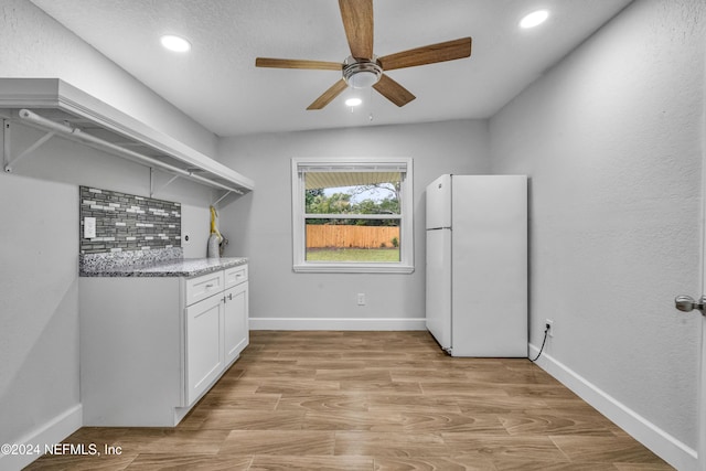 interior space with white cabinetry, white fridge, light hardwood / wood-style floors, lofted ceiling, and decorative backsplash