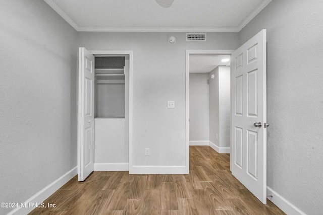 unfurnished bedroom with crown molding, a closet, and hardwood / wood-style flooring