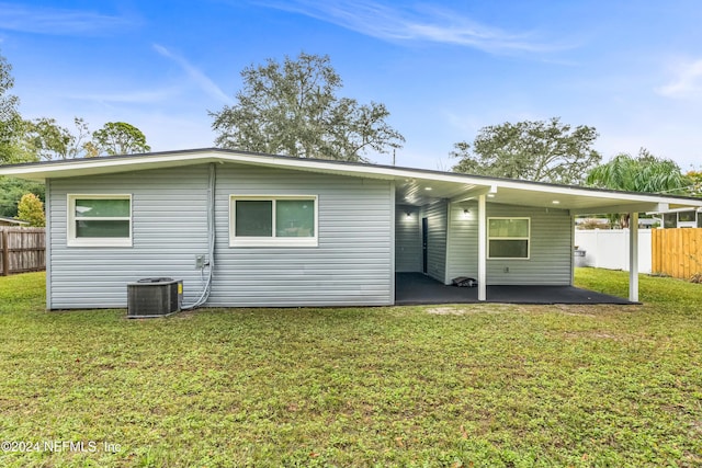 rear view of house featuring a lawn and central AC