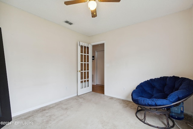 living area with ceiling fan and carpet