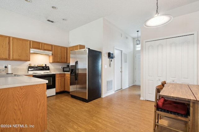 kitchen with stainless steel fridge, white range with electric cooktop, sink, light hardwood / wood-style floors, and decorative light fixtures