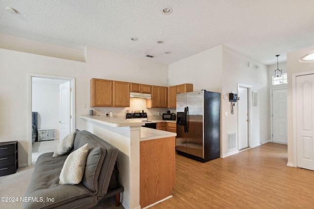 kitchen with kitchen peninsula, hanging light fixtures, a textured ceiling, light wood-type flooring, and black appliances