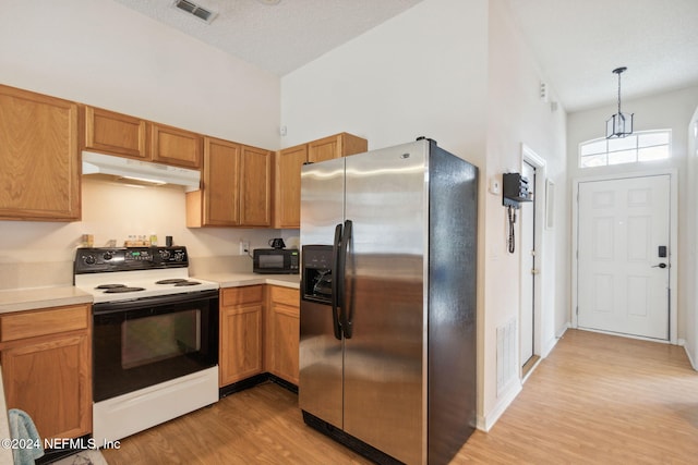 kitchen featuring stainless steel fridge, decorative light fixtures, light wood-type flooring, and white electric stove