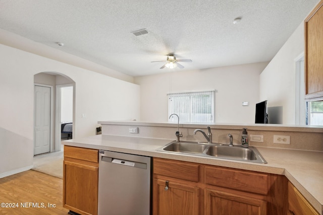 kitchen with ceiling fan, a textured ceiling, dishwasher, light hardwood / wood-style floors, and sink