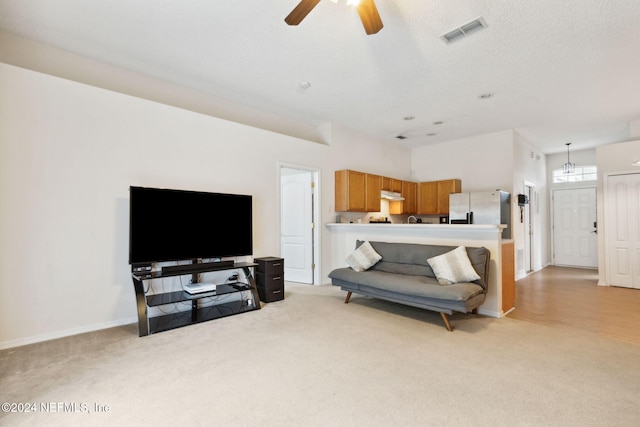 carpeted living room with ceiling fan and a textured ceiling