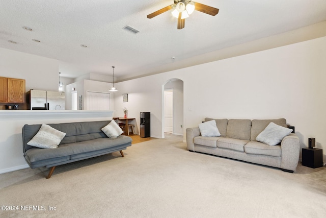 carpeted living room featuring a textured ceiling and ceiling fan