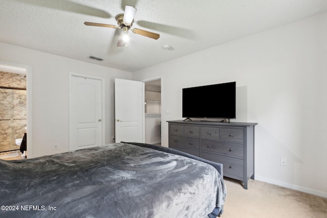 unfurnished bedroom featuring ceiling fan, ensuite bath, a textured ceiling, and light colored carpet