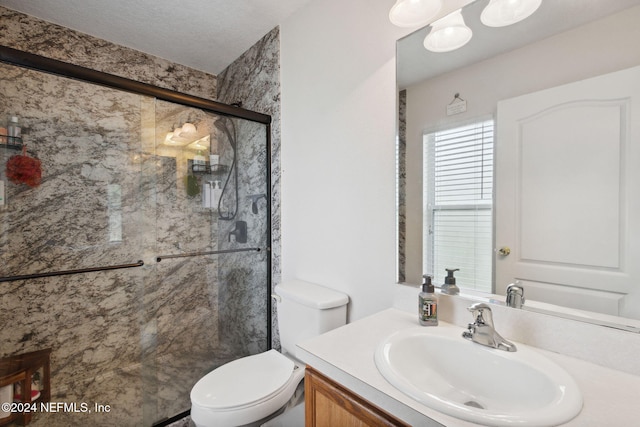 bathroom with vanity, a textured ceiling, toilet, and walk in shower