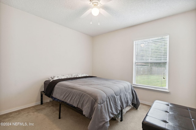 bedroom featuring multiple windows, a textured ceiling, light colored carpet, and ceiling fan