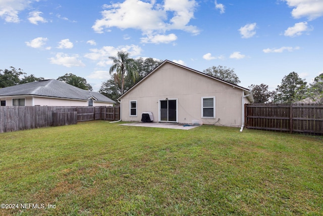 back of house featuring a patio area and a lawn