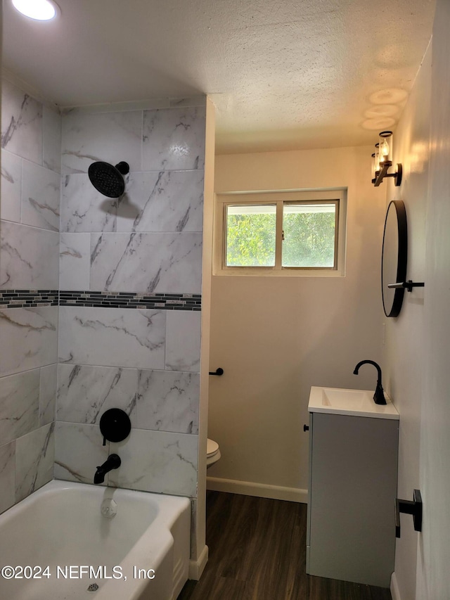 full bathroom with tiled shower / bath, a textured ceiling, wood-type flooring, toilet, and vanity