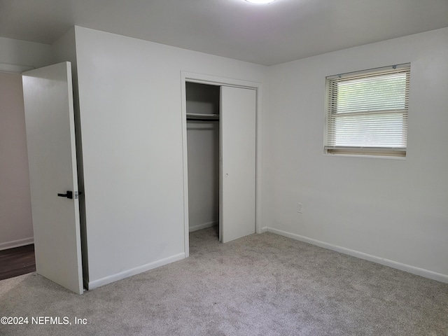 unfurnished bedroom with light colored carpet and a closet