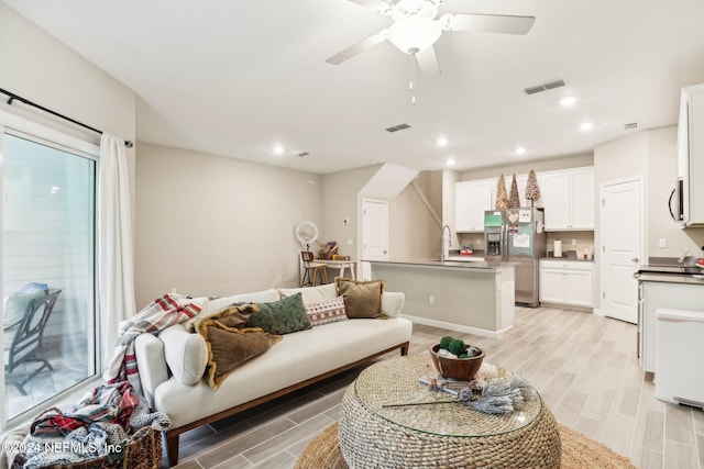 living room with ceiling fan, light hardwood / wood-style flooring, and sink