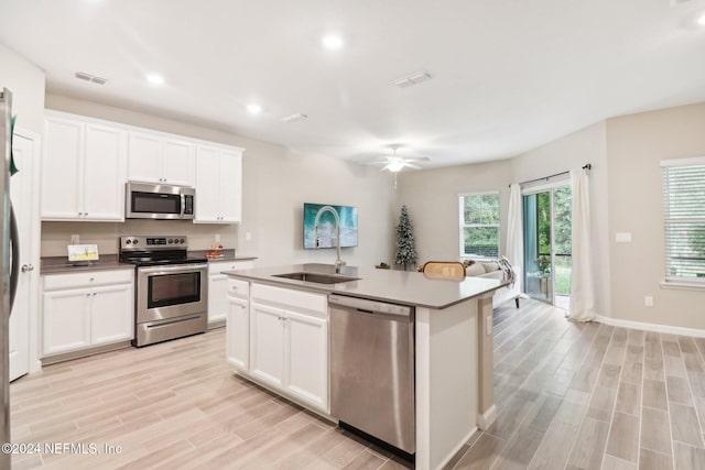 kitchen with ceiling fan, an island with sink, light hardwood / wood-style floors, white cabinets, and appliances with stainless steel finishes