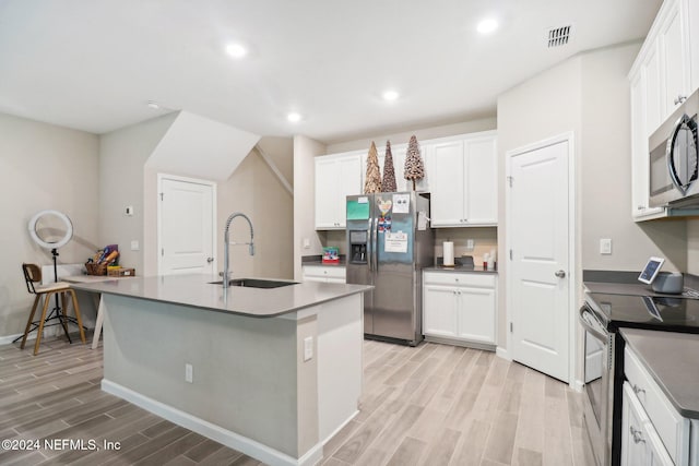 kitchen featuring a kitchen island with sink, sink, white cabinets, and appliances with stainless steel finishes