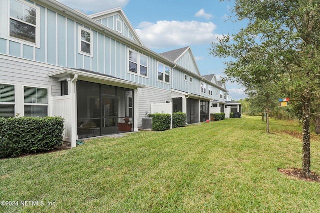 back of house with a lawn, a sunroom, and central air condition unit