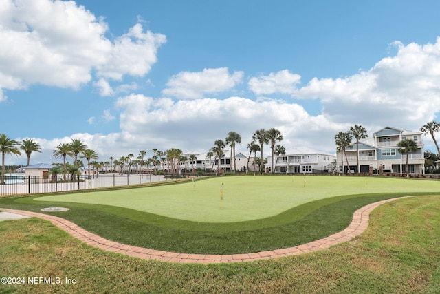 surrounding community with view of golf course and fence