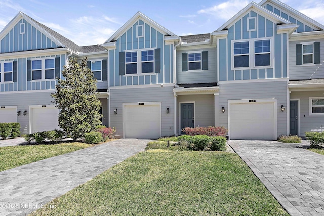 multi unit property with a garage, decorative driveway, a front lawn, and board and batten siding