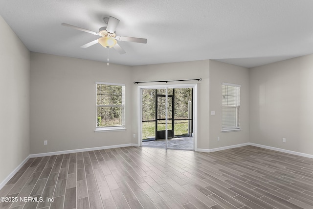 empty room with ceiling fan, wood finished floors, and baseboards