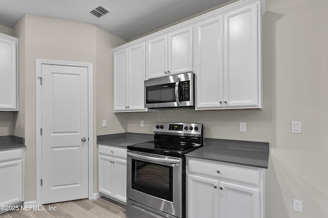 kitchen featuring dark countertops, white cabinetry, visible vents, and stainless steel appliances