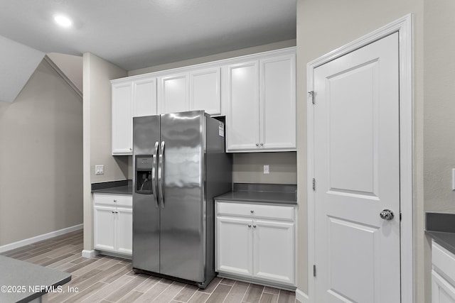 kitchen featuring wood finish floors, white cabinetry, dark countertops, and stainless steel fridge with ice dispenser